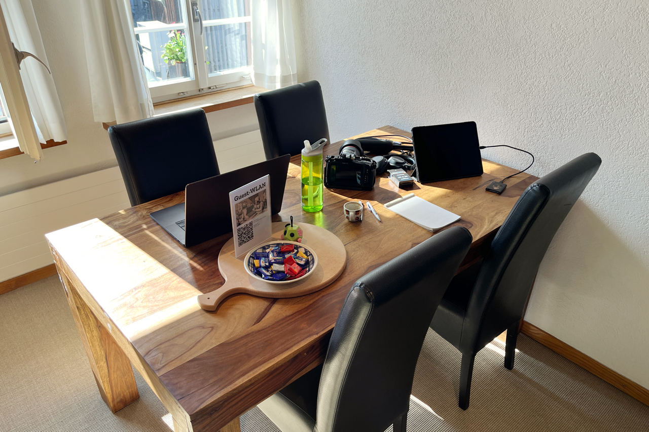 Tisch mit Laptop, einem iPad, einer Kamera und einer Wasserflasche